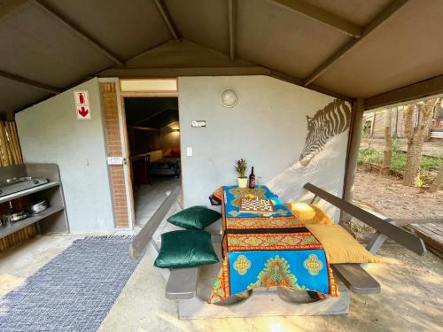 a tent with a table and a zebra painted on the wall at Hazyview Adventure Backpackers in Hazyview