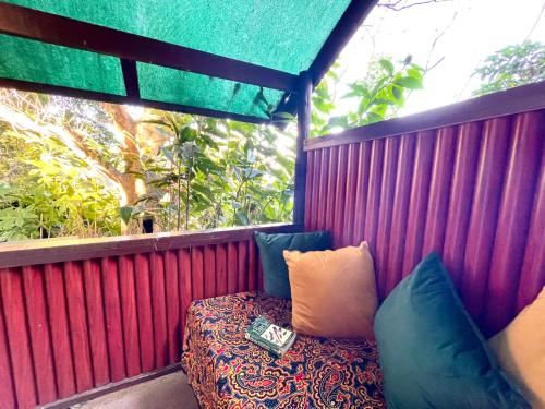 a balcony with a bench with pillows and a book at Hazyview Adventure Backpackers in Hazyview