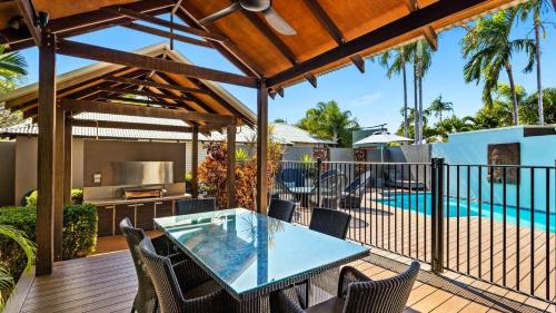 a patio with a table and chairs and a swimming pool at The Pearle of Cable Beach in Broome