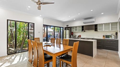 a kitchen and dining room with a wooden table and chairs at The Pearle of Cable Beach in Broome