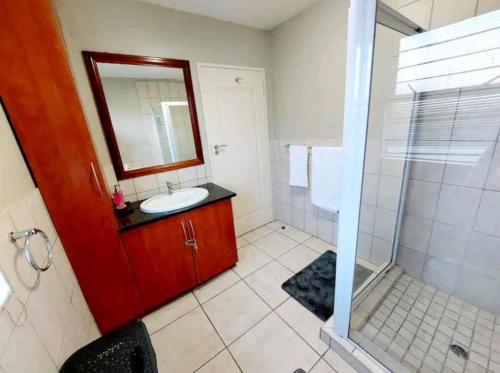 a bathroom with a sink and a shower with a mirror at Gautrain Hatfield Lovely Studio in Pretoria