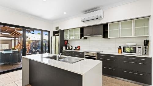 a kitchen with black cabinets and a white counter top at The Pearle of Cable Beach in Broome