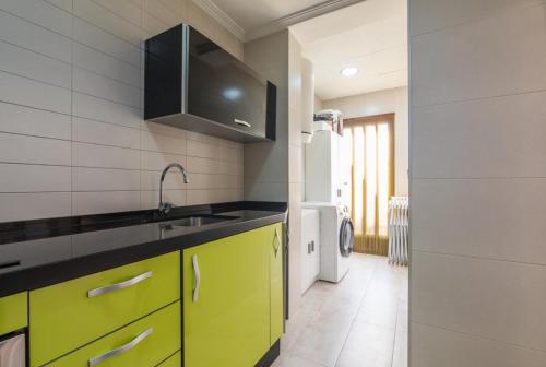 uma cozinha com armários amarelos e um lavatório em Casa Alanis em Gran Alacant