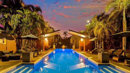 a swimming pool in a resort with palm trees at The Pearle of Cable Beach in Broome