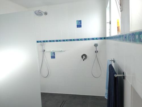 baño blanco con ducha de azulejos azules en Jochen's Haus - Zimmer & Bad, en Siershahn