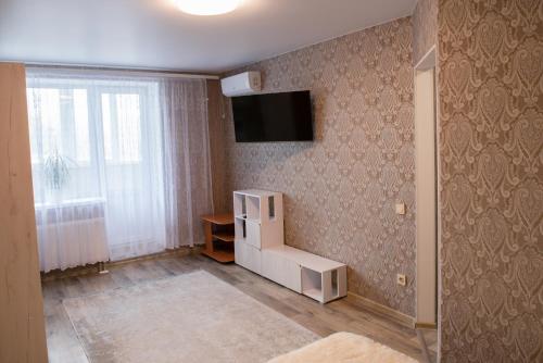 Habitación con nevera blanca y TV en la pared. en Академіка Корольова 20 1, en Cherkasy