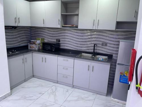 una cucina con armadi bianchi e lavandino di Thistle Greens Apartment a Ikeja