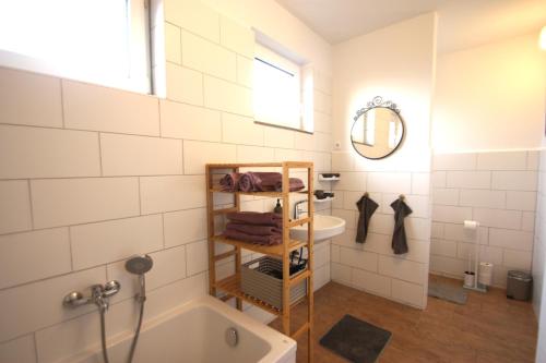 een badkamer met een bad, een wastafel en een spiegel bij Möwennest III in Emden