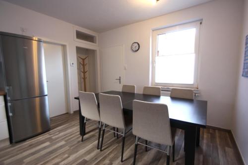 a dining room with a table and chairs and a refrigerator at Moderne Ferienwohnung mit Terrasse & Garten Möwennest III in Emden
