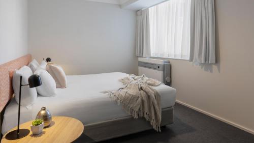Schlafzimmer mit einem Bett, einem Tisch und einem Fenster in der Unterkunft Oaks Perth Hotel in Perth