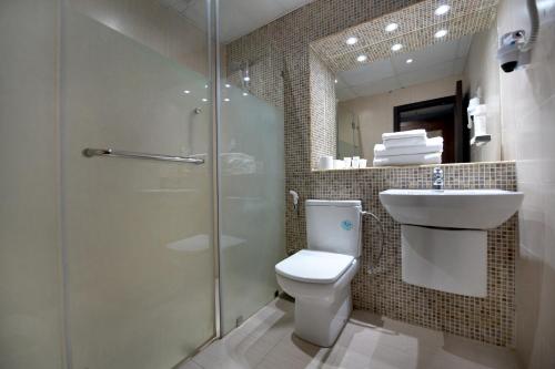 a bathroom with a shower and a toilet and a sink at Carlton Tower Hotel Kuwait in Kuwait