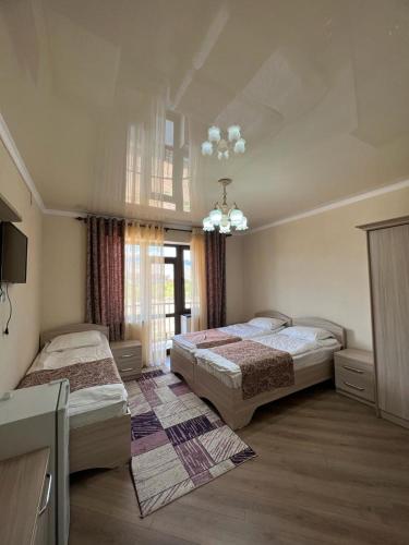 1 dormitorio con 2 camas y lámpara de araña en Гостевой дом RAZAM en Bosteri