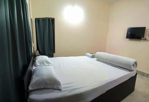a bedroom with a large white bed with green curtains at Gaur Homestay AC Rooms in Puri