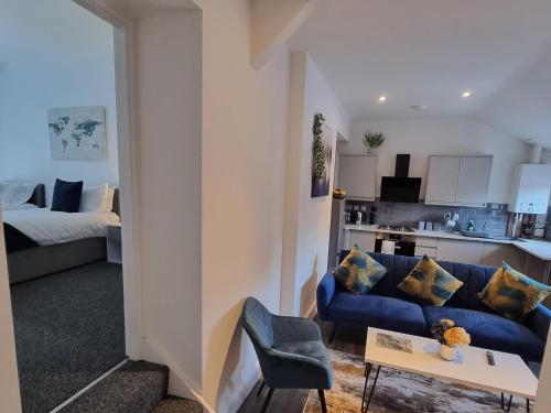 sala de estar con sofá azul y cocina en Sandbach Apartments en Sandbach
