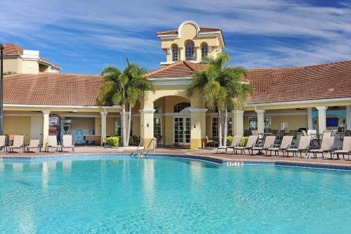 a pool in front of a house with chairs and a building at Vista Cay Resort by Millenium at Universal Blvd. in Orlando