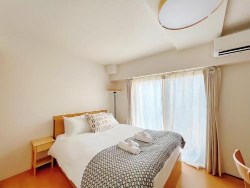 a bedroom with a large white bed and a window at NALY. TENMA AFP Apartment in Osaka