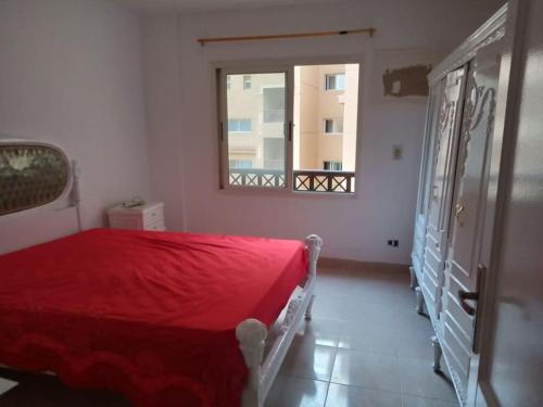 1 dormitorio con cama roja y ventana en Furnished apt for rent Have fun, en Madinaty