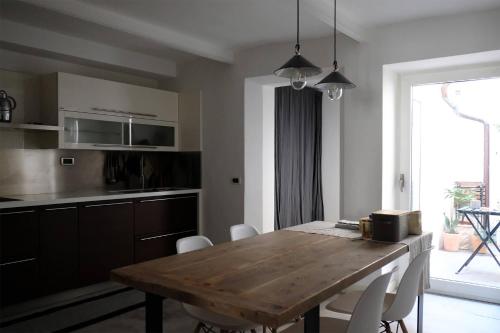 a kitchen with a wooden table and white chairs at Esclusiva Casa indipendente in Centro in Udine