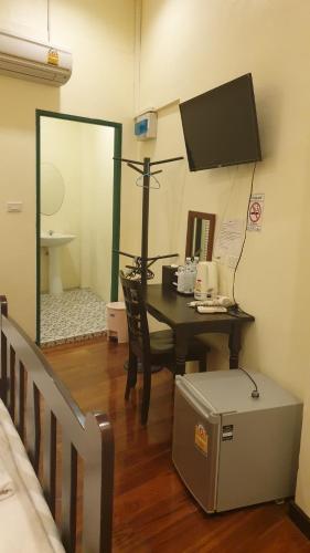 Zimmer mit einem Tisch, einem Spiegel und einem Bett in der Unterkunft Thunyaporn Hostel in Trang