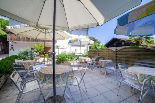 an outdoor patio with tables and chairs and umbrellas at Pension Kofler in Vollan