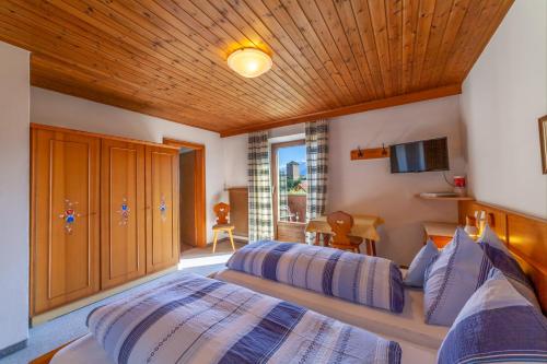 a bedroom with two beds and a television in it at Pension Kofler in Vollan