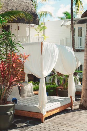 a bed with white curtains sitting on a deck at La Maison 20 Degrés Sud - Relais & Châteaux in Grand Baie