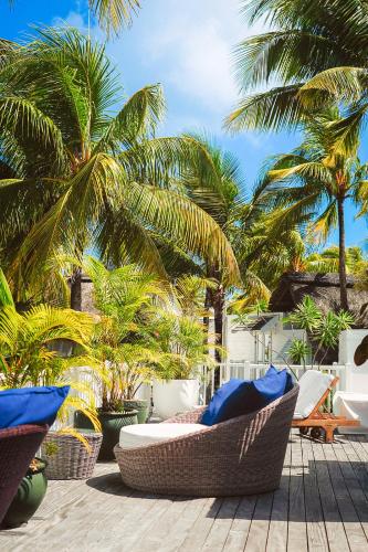 a patio with wicker chairs and palm trees at La Maison 20 Degrés Sud - Relais & Châteaux in Grand Baie