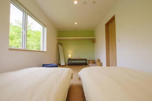 2 camas blancas en una habitación con ventana en Furano Hidden Hill【FHH】, en Kami-furano