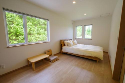a bedroom with a bed and two windows at Furano Hidden Hill【FHH】 in Kami-furano