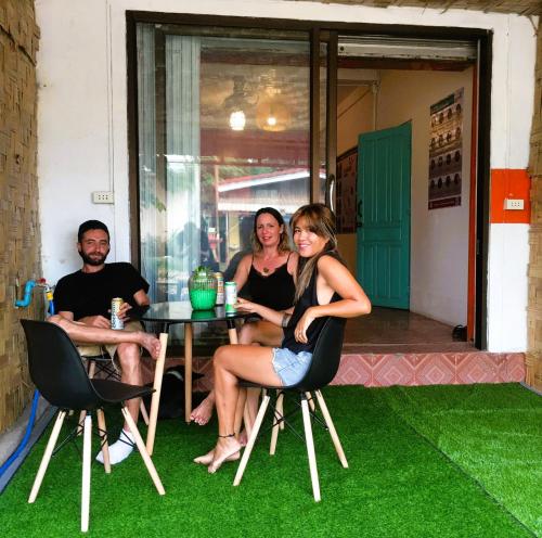 a group of people sitting at a table with green grass at Bamboo Hostel in Thakhek