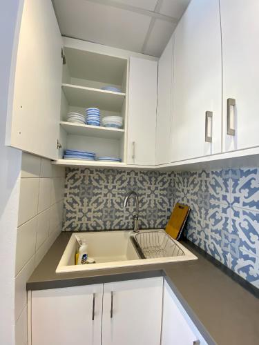 a kitchen with white cabinets and a sink at Cozy blue in Ialyssos