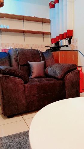 a brown couch in a living room with a table at Georgia Furnished Apartments in Machakos