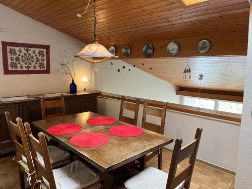 un comedor con una mesa de madera con placas rojas. en Waldhaus Max, en Bad Wildbad