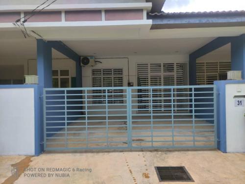 uma casa com uma cerca azul em frente em Aisyah Homestay Kuantan - Jaya Gading em Kampong Seri Permatang Gading
