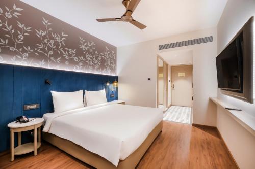 a bedroom with a large white bed and a blue wall at 7 Apple Hotel Jal Mahal, Jaipur in Jaipur