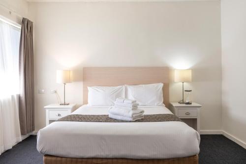 Una habitación de hotel con una cama con toallas. en Adelaide Granada Motor Inn, en Adelaida