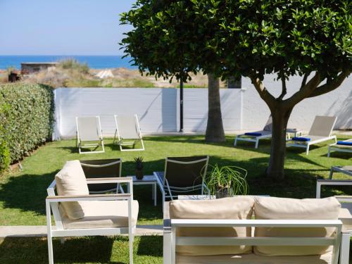 a group of chairs and tables and a tree at Sea La Vie in Adelianos Kampos