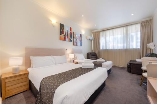 a hotel room with a large bed and a chair at Adelaide Granada Motor Inn in Adelaide