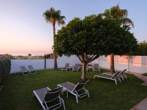a group of chairs and a tree on a lawn at Sea La Vie in Adelianos Kampos