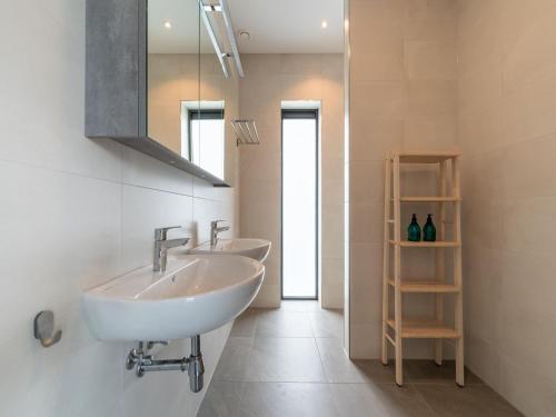 La salle de bains est pourvue de 2 lavabos et d'un miroir. dans l'établissement Water villa with garden near Harderwijk, à Zeewolde