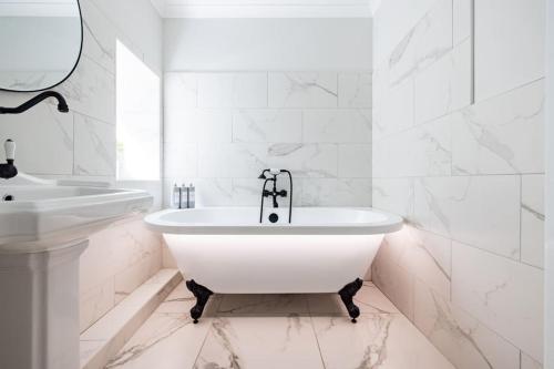 a white bathroom with a tub and a sink at Luxurious Complex: 2 barns together edge of Frome in Frome