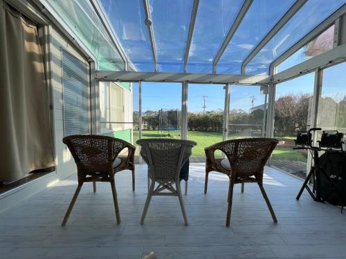 a screened in porch with two chairs and a table at Nalu kujukuri in Kido