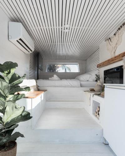 a living room with white furniture and a plant at Leobus-לאו באס in Menaẖemya