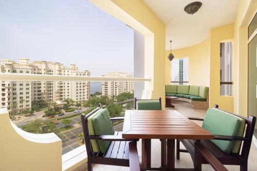 a balcony with a wooden table and chairs and a large window at Royal Club By RVHR, Palm Jumeirah in Dubai