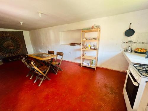 a kitchen with a red floor and a table and chairs at Habitaciones Wallpari Sonqo alto hospedaje medicina temazcal in Pisac