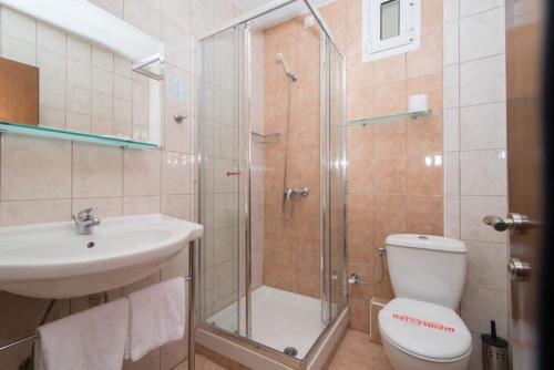 a bathroom with a shower and a toilet and a sink at Hotel Europe in Paralia Katerinis