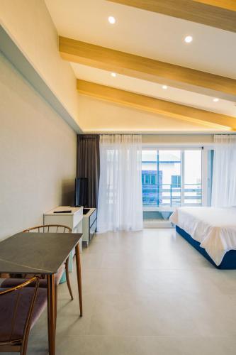 a bedroom with a bed and a table and a window at Unicorn Jeju in Seogwipo