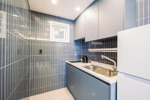 a bathroom with blue and white tiled walls and a sink at Unicorn Jeju in Seogwipo