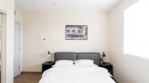 a white bedroom with a bed and a picture on the wall at Three-Bedroom Hollywood Condo in Los Angeles