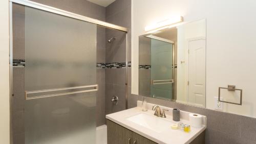 a bathroom with a sink and a shower with a mirror at Three-Bedroom Hollywood Condo in Los Angeles